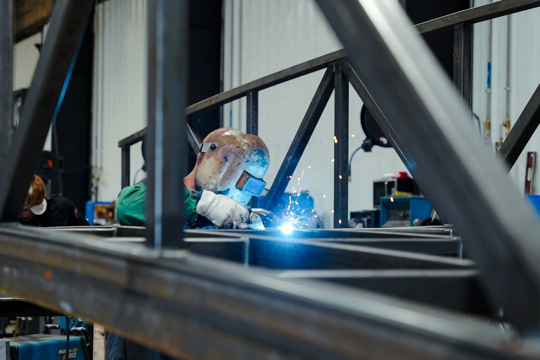 Welder working inside a large steel frame in the THG shop